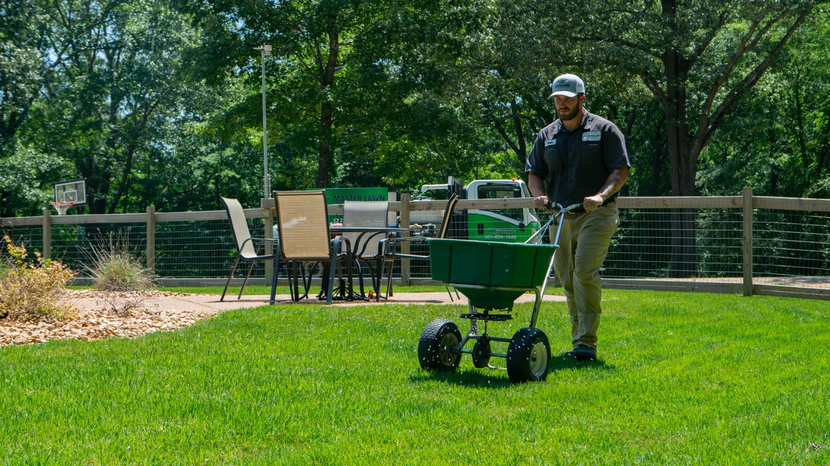 Lawn care technician treats lawn with pre emergent weed control fertilizer