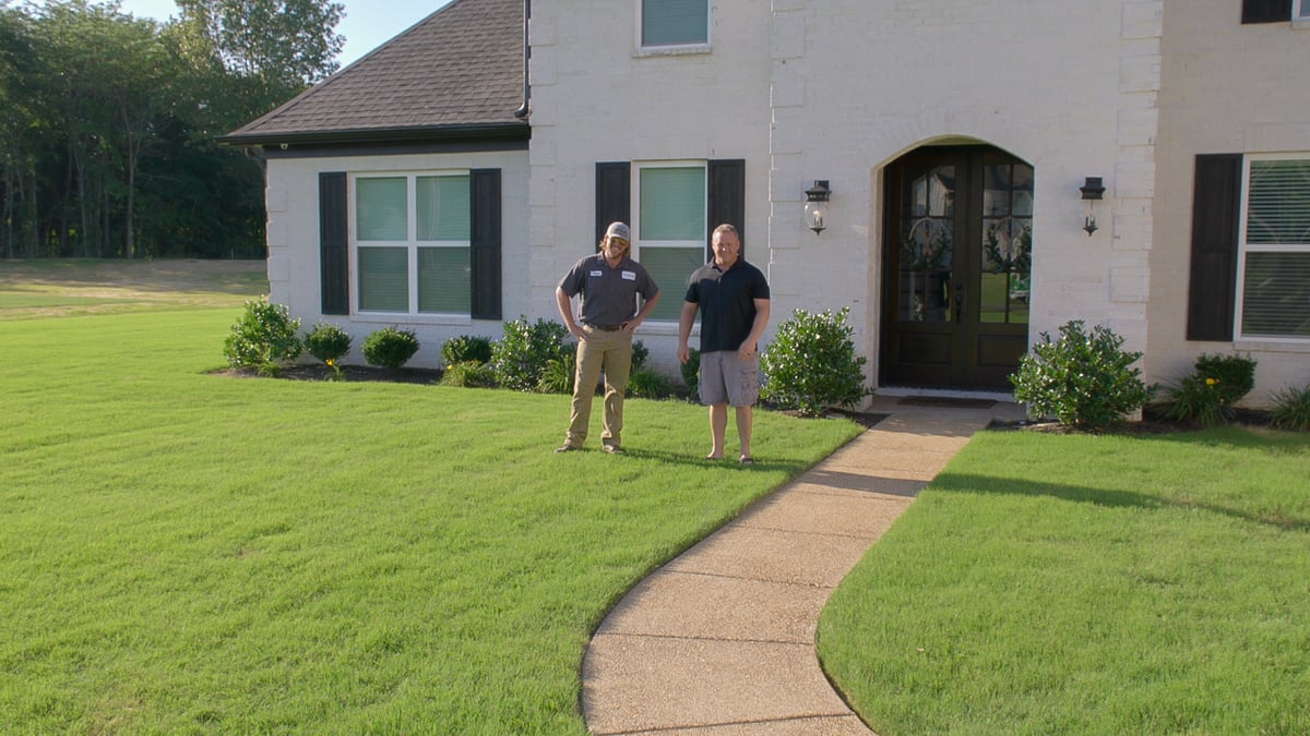 customer and lawn care technician looking at grass