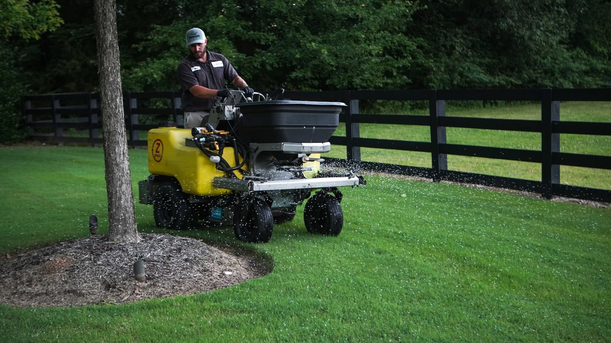 lawn care technician fertilizes lawn
