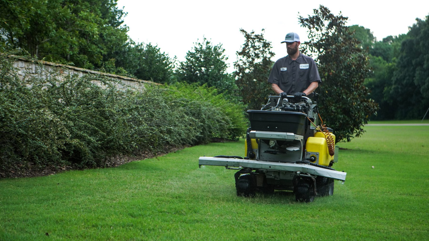 lawn care technician spraying with ride on sprayer