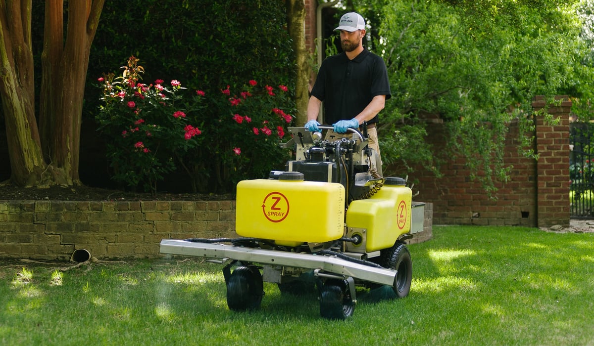 lawn care technician sprays for weeds