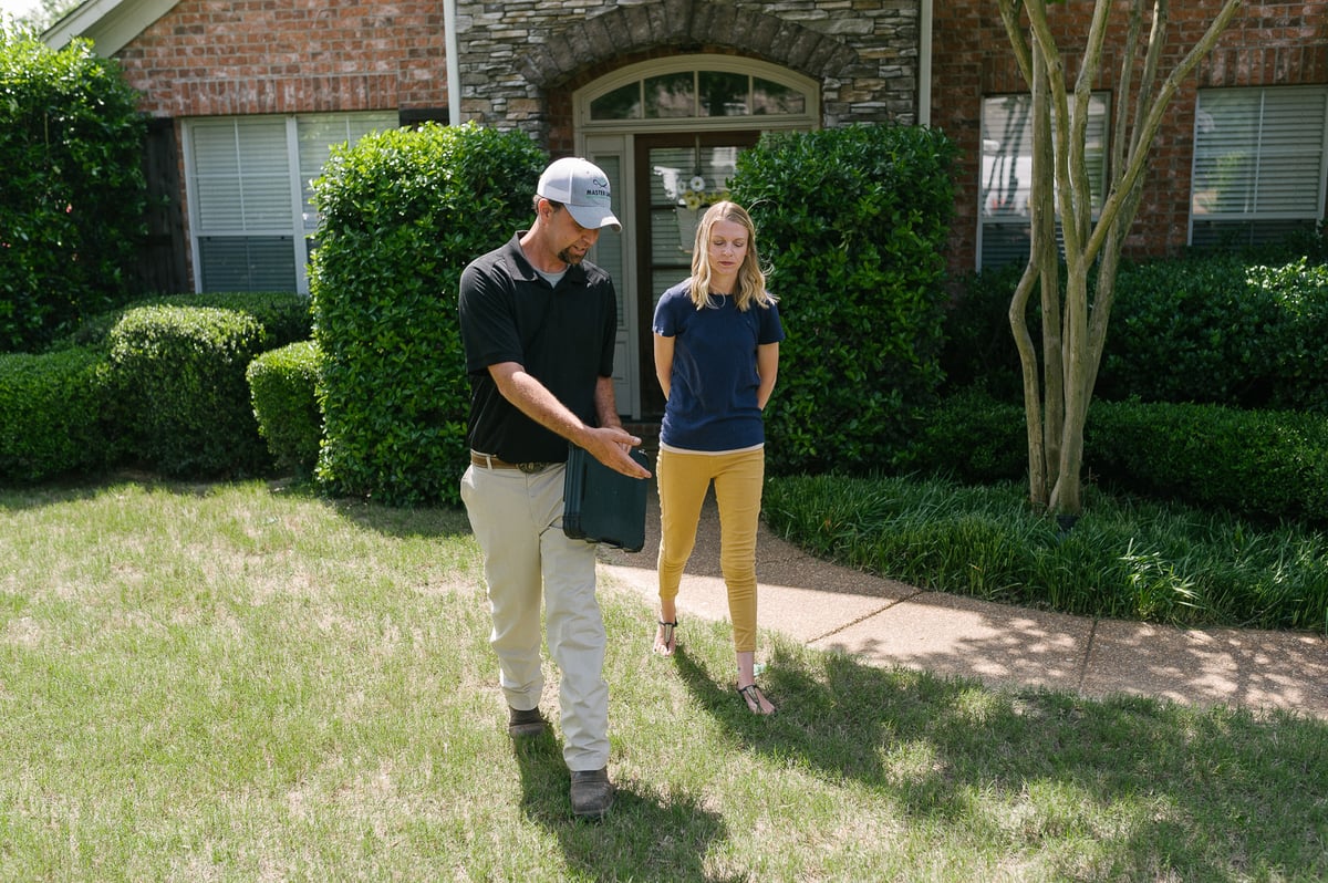 lawn care technician discusses lawn with customer