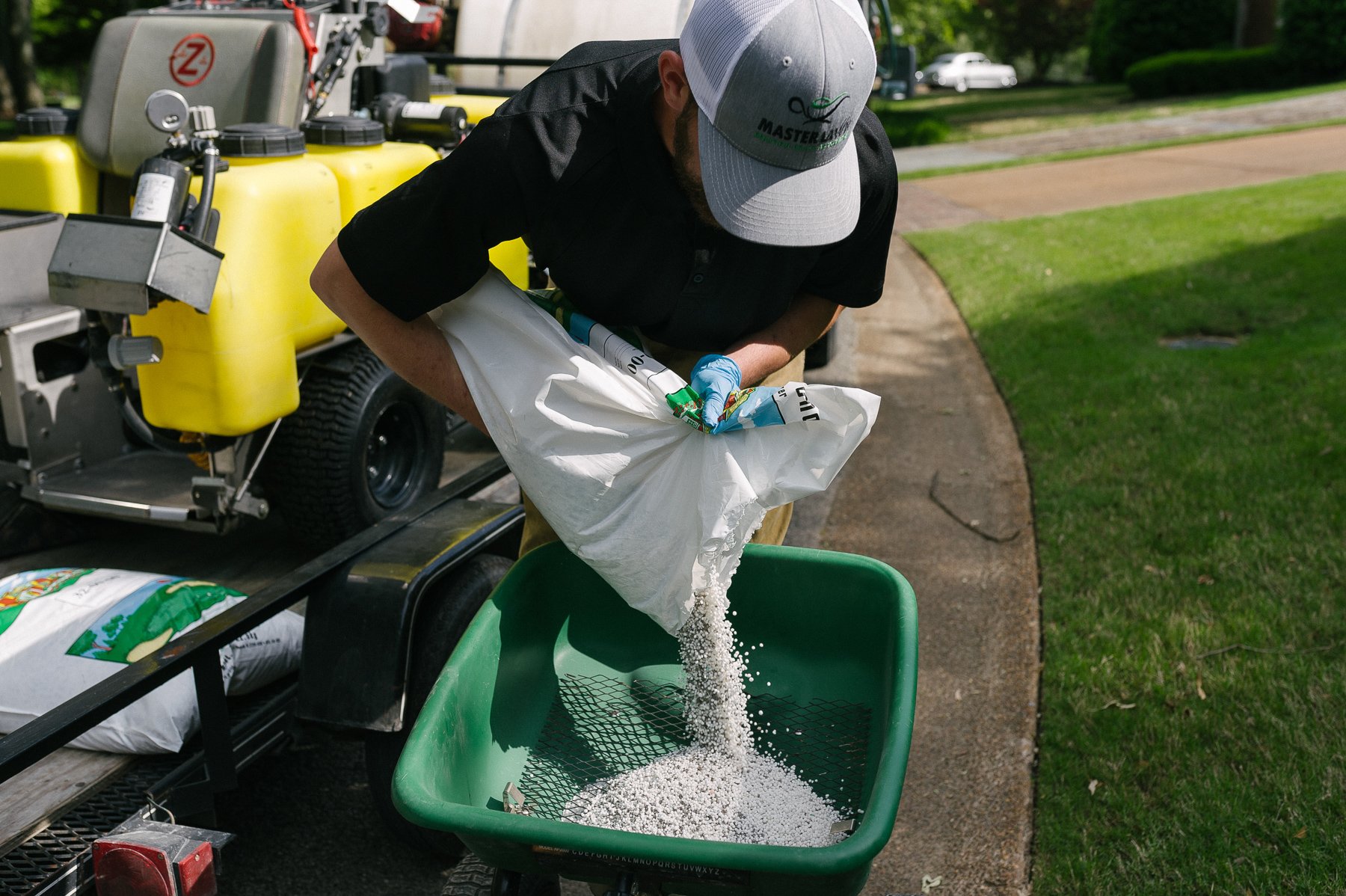 landscape technician pouring granular fertilizer