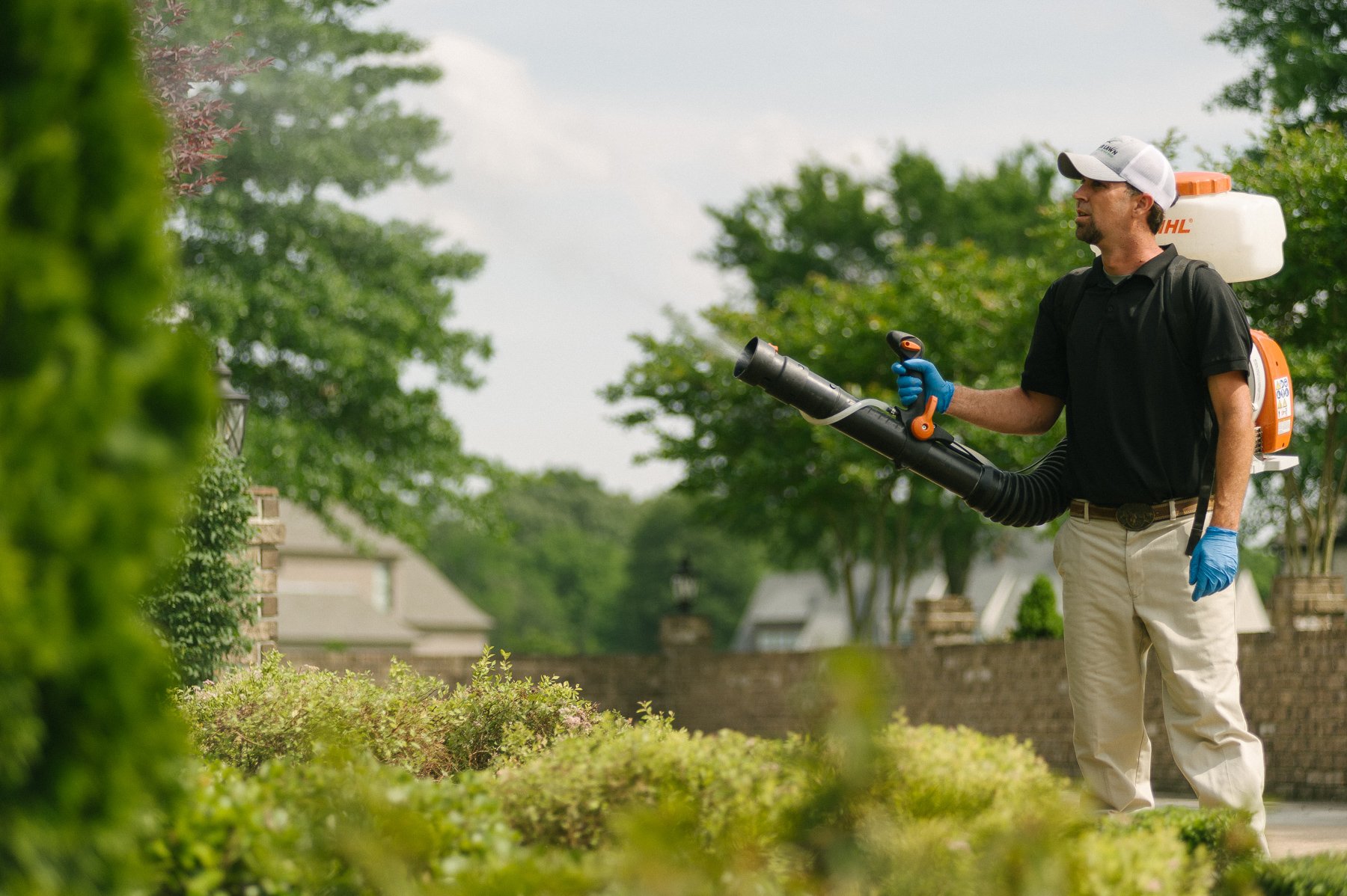 mosquito control technician spraying shrubs
