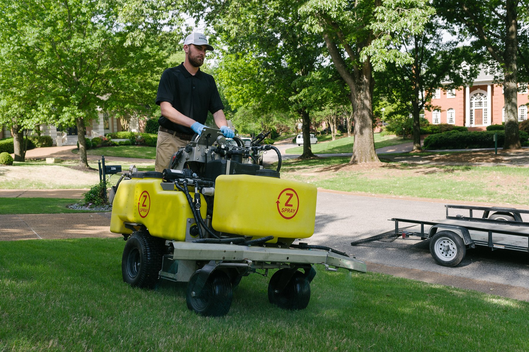 Lawn care technician using a ride-on machine sprayer