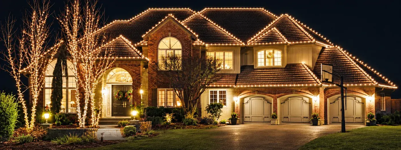 Brick home with custom holiday lighting on the roofline and trees